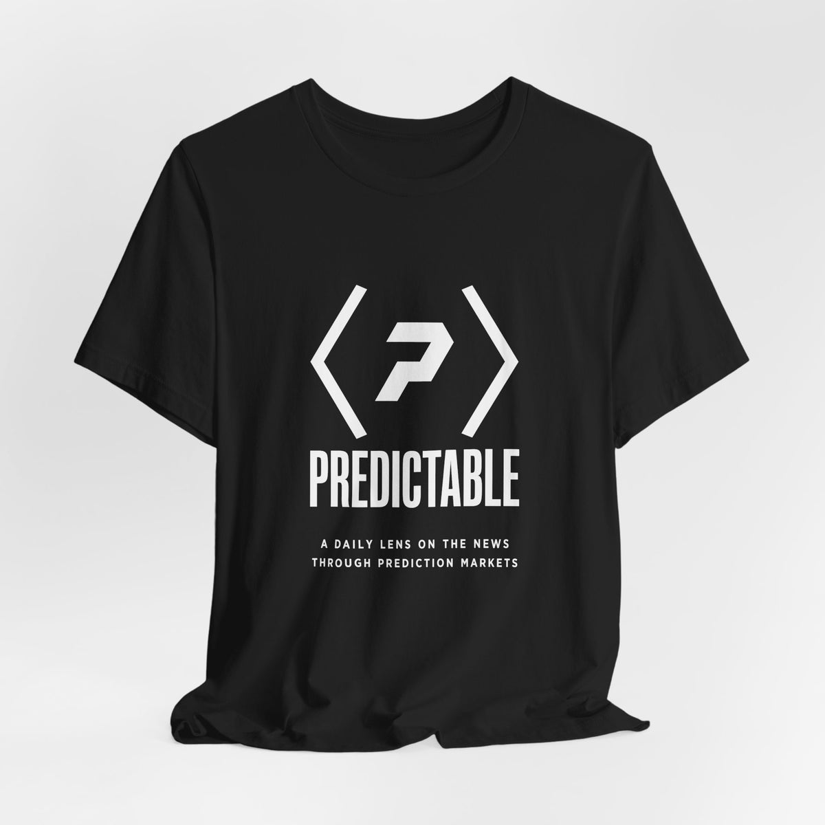 Black PREDICTABLE Wordmark Lockup Tee draped against a light gray backdrop.